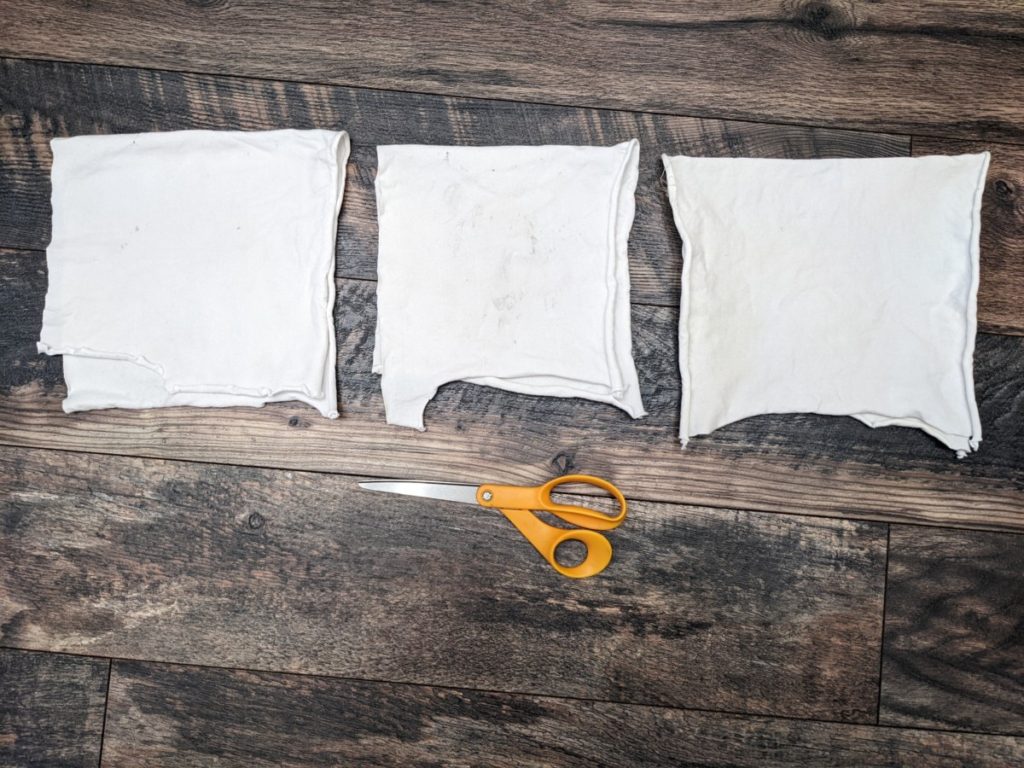three pieces of white cloth folded in half net to a pair of scissors